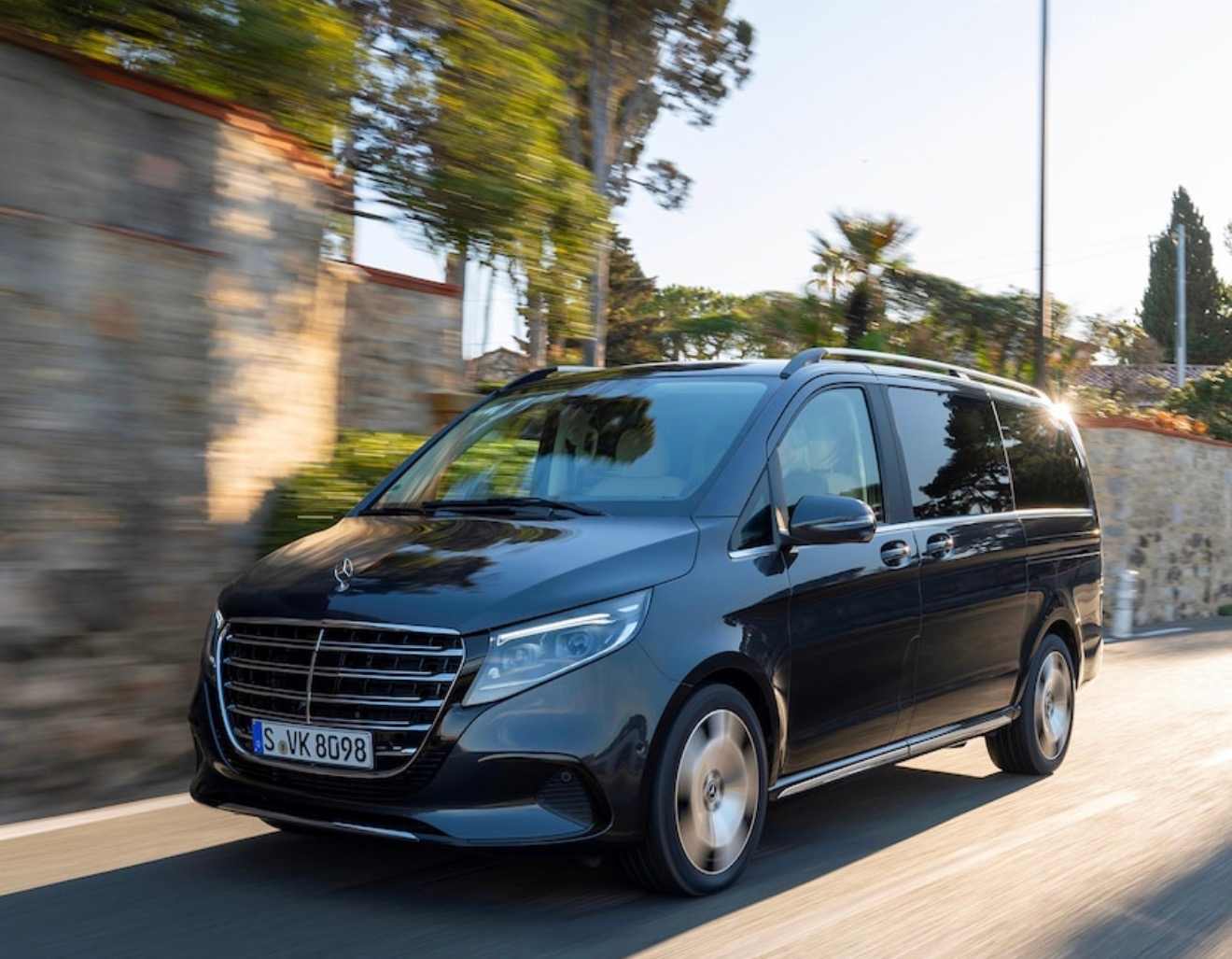 Van noir de VTC en circulation sur une route provençale bordée de pins